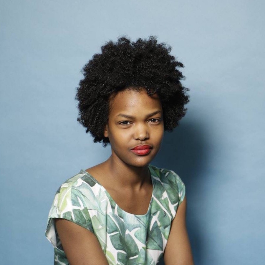 Jessica Angima headshot. Wearing green top against a blue background